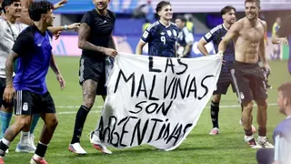 Argentina players hold a white banner that has "Las Malvinas son Argentinas", which translates as "The Falklands are Argentine", written in black text.
