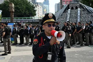 A member of the Secretariat of Citizen Security uses a megaphone to give instructions to personnel evacuated from several buildings in Mexico City after an earthquake on Friday. Photo: AFP