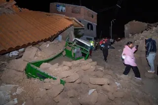 Residents gingerly navigate the rocks and debris of buildings that collapsed after the earthquake