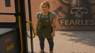 A woman stands at a bus door