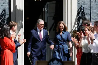 英國首相施凱爾（左）20日最後一次以首相身分步出唐寧街10號官邸，妻子維多利亞（右）伴隨，一同接受提早聚集在門外的支持者、執政團隊與公務體系成員鼓掌歡呼。（英國首相府提供）中央社記者陳韻聿傳真　115年7月20日