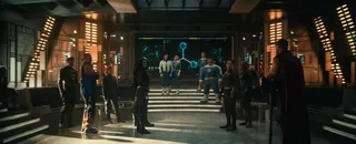 various assembled superheros standing awkwardly in a large room
