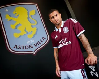 João Gomes poses next to an Aston Villa crest