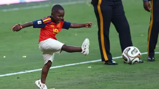 Kenye smiles as he kicks a football on the pitch