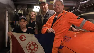 Russ Matthews pictured holding an Explorers Club flag with members of his team and Josh Gates