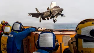 US service members aboard the USS Boxer amphibious assault ship watch a US fighter jet in flight. File photo