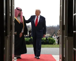 President Trump and Crown Prince Mohammed bin Salman walk together, Trump in a dark suit, the Crown Prince in traditional dress