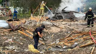 Emergency services clear through the rubble following a Russian missile strike just outside of Kyiv. Firefighters can be seen extinguishing a car fire in the background