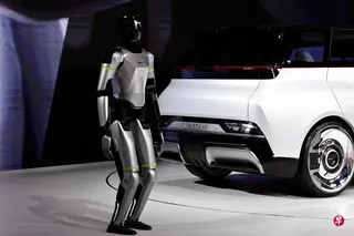 4月24日，北京国际汽车展览会上，一台人形机器人站在吉利汽车发布的Robotaxi原型车“Eva Cab”旁。 （路透社）