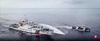 中菲两国船只星期四（7月23日）在具主权争议的南中国海黄岩岛附近对峙，中国海警船（左）向菲律宾渔业公务船发射水炮，予以驱离。菲律宾海岸警卫队称，中国海警船曾逼近菲律宾渔业船50米以内，并喷射水炮长达两分钟。中国海警局则称，“现场操作专业规范、正当合法”。 （“中国海警”微信公众号）