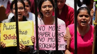 A group of three students during a protest carrying banners demanding an end to paper leaks.