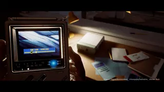 A close-up of a handheld TV device reading FINE TUNE - SEARCHING on its screen, held near a cluttered desk with papers and a lamp.