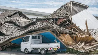 A house is seen collapsed onto a car in Yatsushiro, Kumamoto prefecture on July 29, 2026