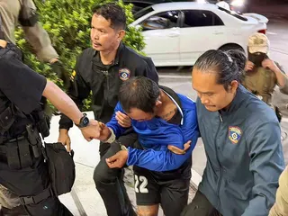 被控殺害俄國兩姊弟的嫌犯塔納(中)遭泰國警方逮捕，被帶往警局接受調查。(歐新社)