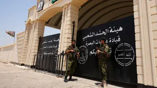 Members of Iraq's Popular Mobilization Forces (PMF) stand guard outside the Basra Operations Command headquarters