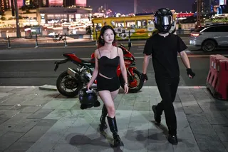 A woman poses for picture with a motorcycle rider offering photo and video service along a street in Chongqing July 20, 2026. — AFP pic