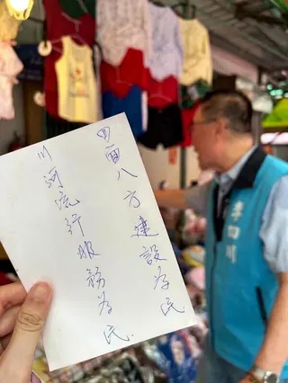 支持者遞上親筆手寫字條，以16字藏頭詩「四面八方建設為民，川河流行服務為民」為李...