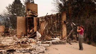 Ash Sollie stands in front of her grandparents' home, where she previously lived, after it was destroyed by a wildfire, in Spokane, Washington, U.S.