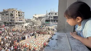 A girl watches the mass funeral of 112 members of the Hassayna and Abu Sharia clans who the Civil Defence says were killed in an Israeli strike in November 2023, in Gaza City, northern Gaza (4 August 2026)