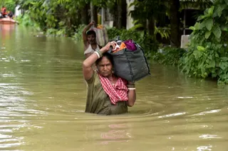 FILE PHOTO: People wade through a flood-affected area with their belongings in Sivasagar, Assam, India, July 23, 2026. REUTERS/Hafiz Ahmed/File Photo