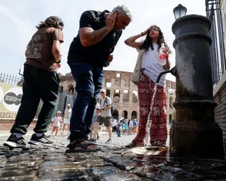 People cool off with water from a fountain near the Colosseum during a heatwave