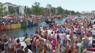 Revellers line Amsterdam canal to watch the annual Pride boat parade