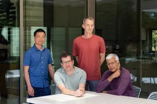 Four men pose on a patio for a photo.