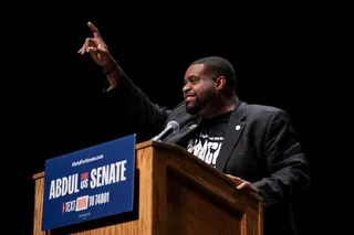 Donavan McKinney wearing a T-shirt and dark suit speaks from a podium at The People v The Powerful rally in Detroit in July