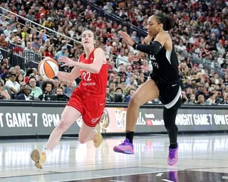 Caitlin Clark dribbles past A'ja Wilson during a WNBA game.