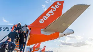 People climb steps onto an easyJet plane.