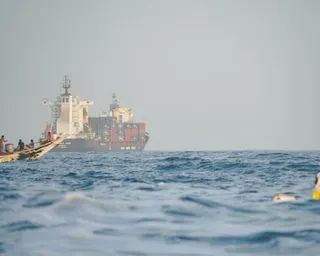 People sail their boats past container ships anchoring near the Strait of Bab al-Mandeb off Yemen’s coast in the Gulf of Aden