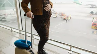 stock image of a pregnant woman with suitcase at an airport