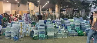 地震发生后，哥伦比亚卡利市一栋建筑物外堆放着大量瓶装水和救援物资。