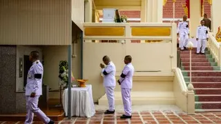 泰国官员周二在暖武里府一所佛教寺庙，在14岁枪手的棺材旁的花圈前致哀。（图取自法新社）