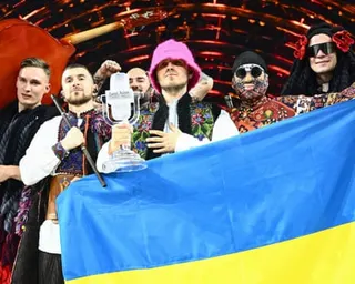 Kalush Orchestra members pose onstage with their Eurovision trophy and Ukraine's flag