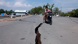 A motorcyclist rides past a crack on the road following the earthquake in East Nusa Tenggara Province, Indonesia.