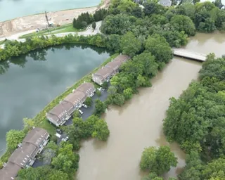 Aerial view of flooding around townhouses, with muddy water surrounding buildings and trees