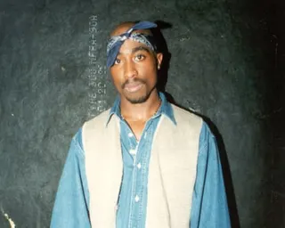 a man in a blue and white shirt and wearing a bandana looks straight ahead
