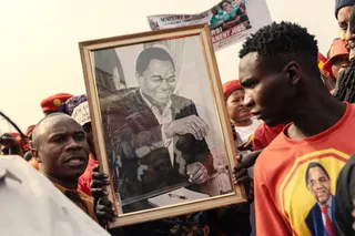 TOPSHOT - Supporters of Zambian incumbent President and United Party for National Development (UPND) presidential candidate Hakainde Hichilema hold his portrait as they cheer during an election campaign rally in Lusaka on August 11, 2026.