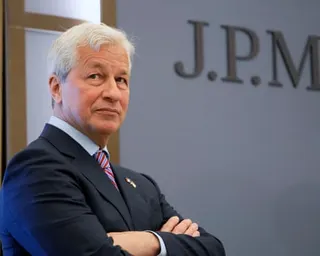 JP Morgan CEO Jamie Dimon stands with arms crossed before a wall with partial lettering