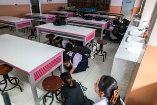 Students hide under tables during a drill by police officers to prepare for an active shooter scenario, at Surasamontree School in Bangkok, Thailand, on Wednesday. Photo: Reuters