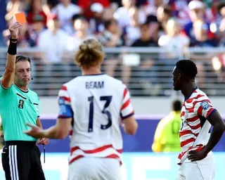 Folarin Balogun (right) is shown a red card by the referee, Raphael Claus.