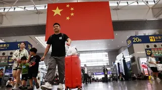 2025年10月3日，在國慶假期出行高峰期間提著行李在上海虹橋火車站行走。