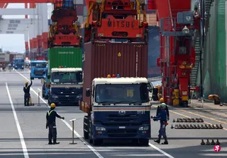 日本7月连续第三个月出现贸易逆差。图为8月20日，日本首都东京一个工业港口的工人将集装箱装载到货船上。 （路透社）