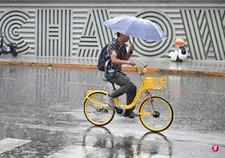 中国据报正考虑申办2028年第33届联合国气候变化大会（COP33）。图为北京一名男子8月15日在雨中骑着脚踏车。 （法新社）