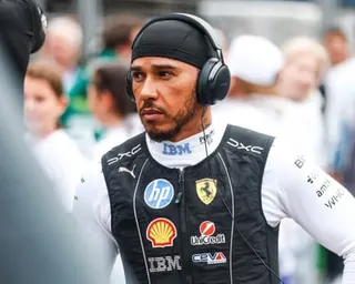 Lewis Hamilton in racing gear, wearing headphones