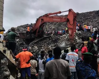 Residents and rescuers search for bodies using an excavator in the dump site in Conakry