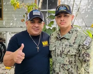 Luis Manuel Aviles gives a thumbs up beside his stepson Joshua in Navy uniform outdoors