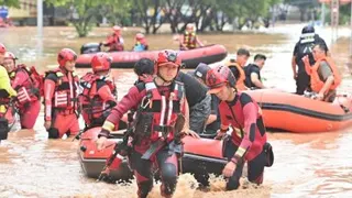 救援人员在广西宁明县县城转移受困民众。（图取自新华社）