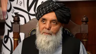 Portrait of Governor Abdullah Sarhadi in his office in Sheberghan. He has a long grey beard and is wearing a black Afghan headdress, and is looking to the left of the camera.